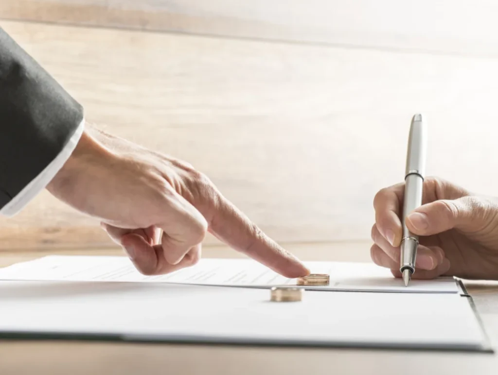 a person signing a document with a pen for filing divorce